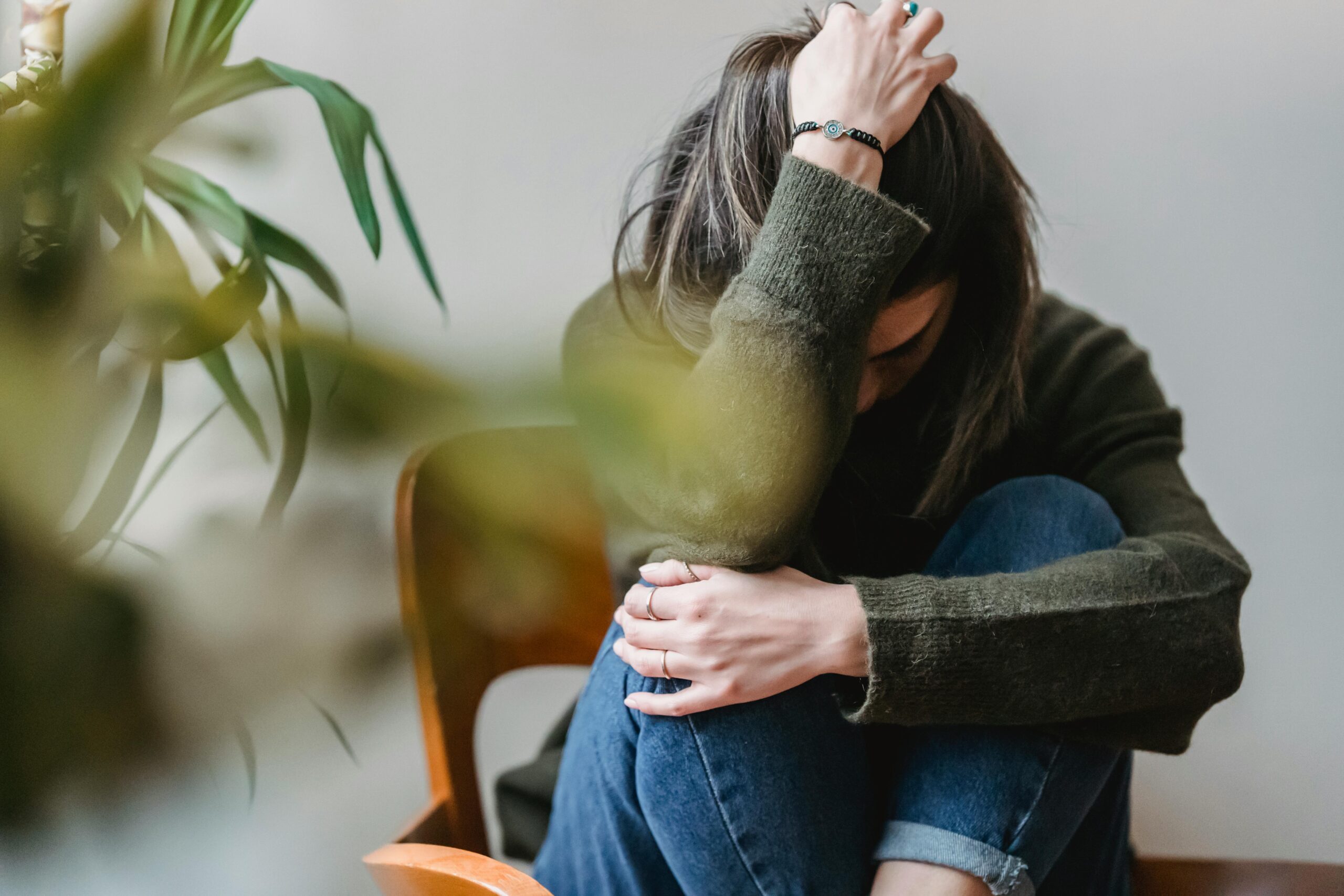 A woman sitting on a chair with her head in her hands.