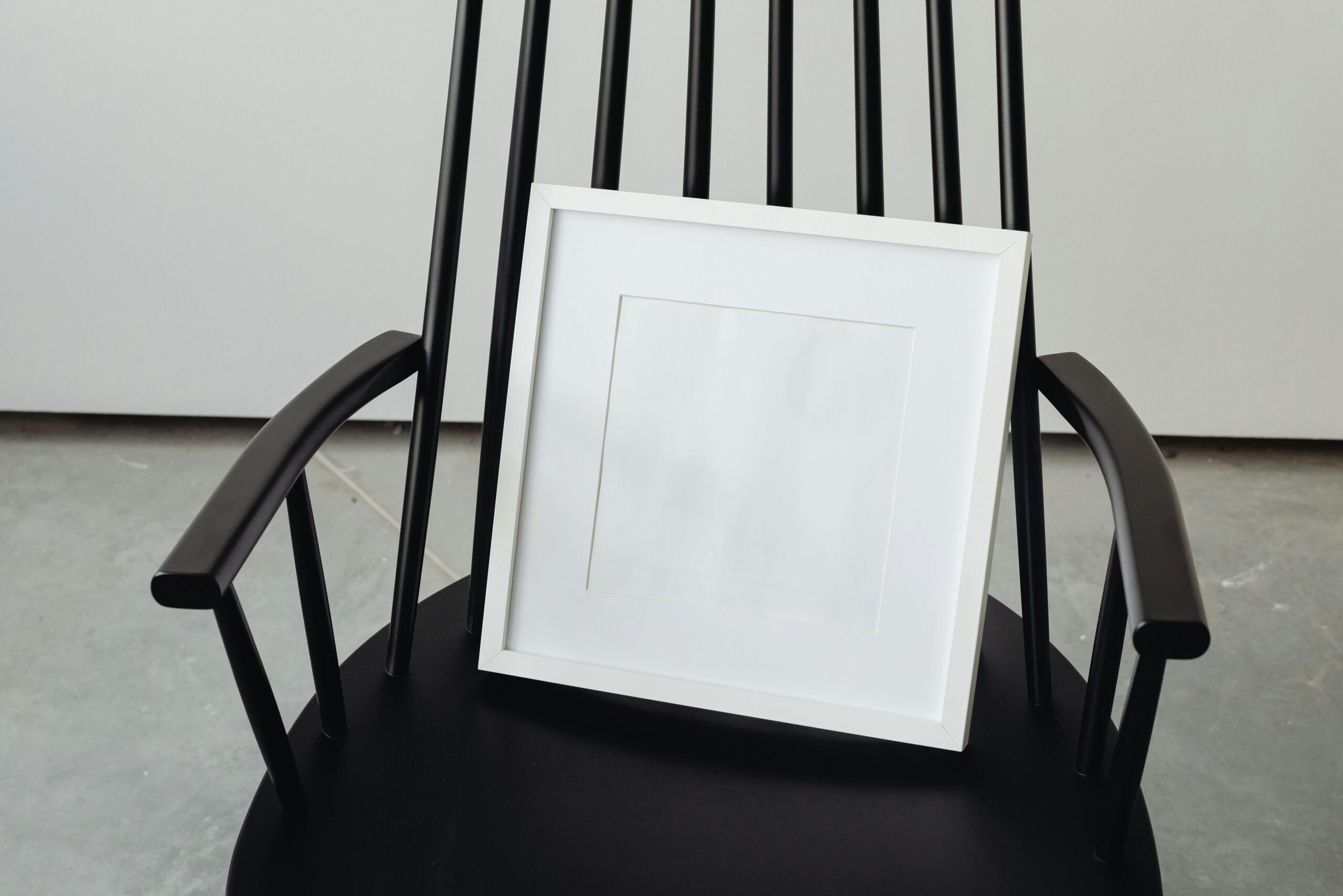 An empty picture frame on top of a wooden chair.